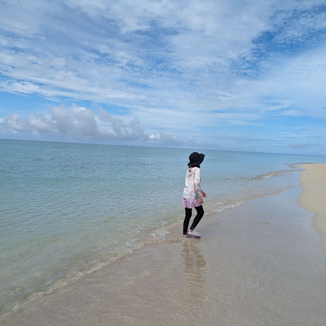 A child walking along the shallow turquoise water of Miyako Island – a top family-friendly destination in the Okinawa islands.
