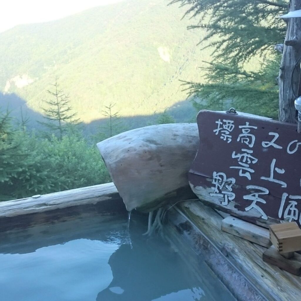 Open-air onsen overlooking mountain peaks at Takamine Onsen — top japanese hot spring travel spot.