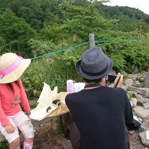 Family taking a scenic break with rice balls during a hike near Takamine Onsen.