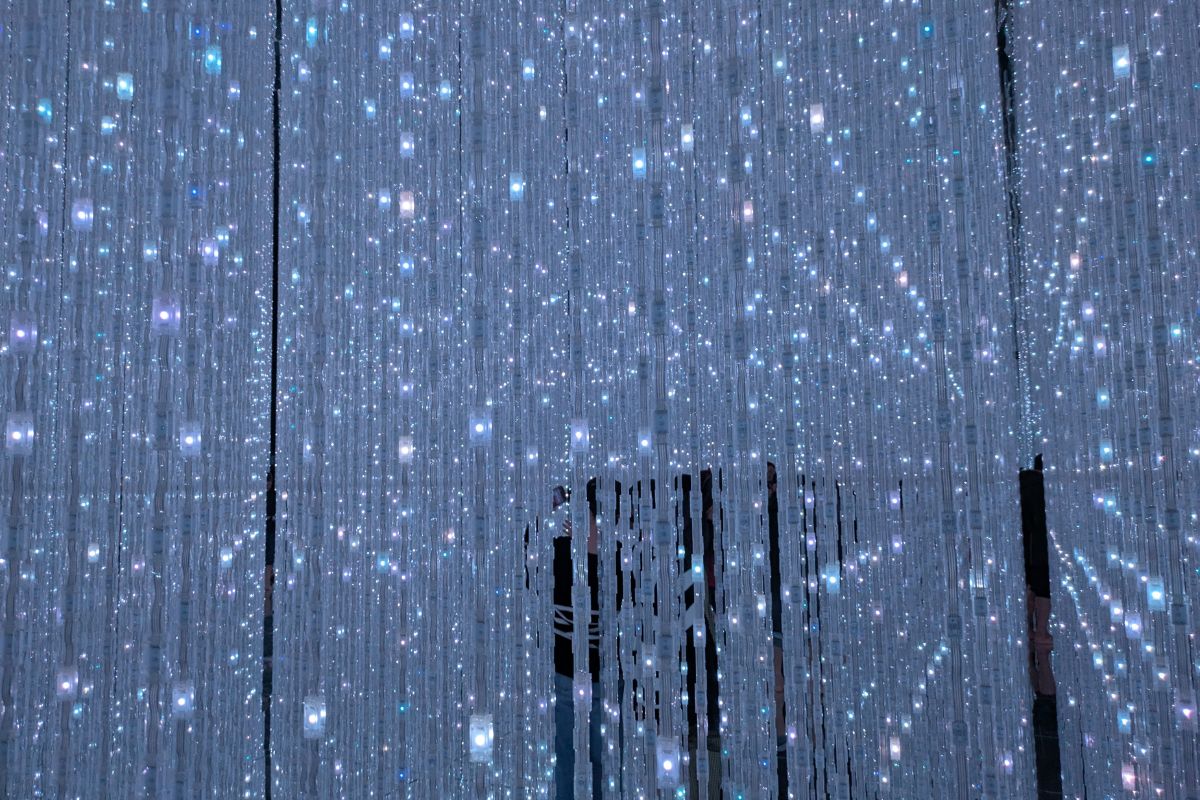A mesmerizing display of countless illuminated strands creating a sparkling, immersive experience at TeamLab Planets in Toyosu. Visitors walk through dazzling LED lights that change colors dynamically, evoking a futuristic and dreamlike atmosphere.TeamLab Planets near Tokyo Disney Hotels.
