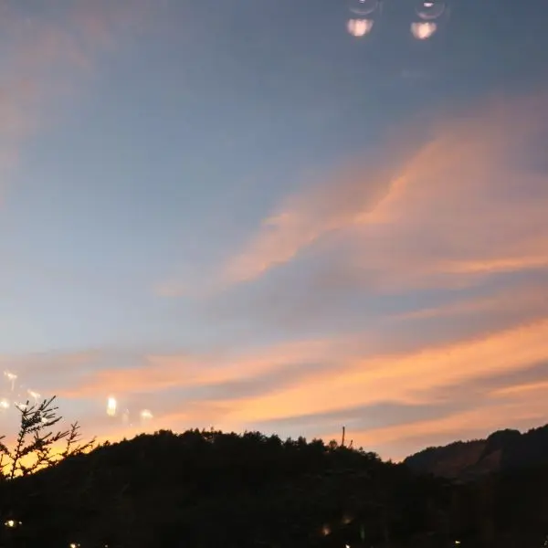 Sunset sky with soft orange clouds above the mountains near Takamine Onsen, creating a serene evening view.