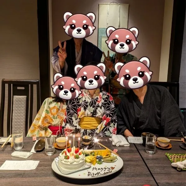 Family gathered around a whole birthday cake with sparkling firework-style candles at the dinner table.