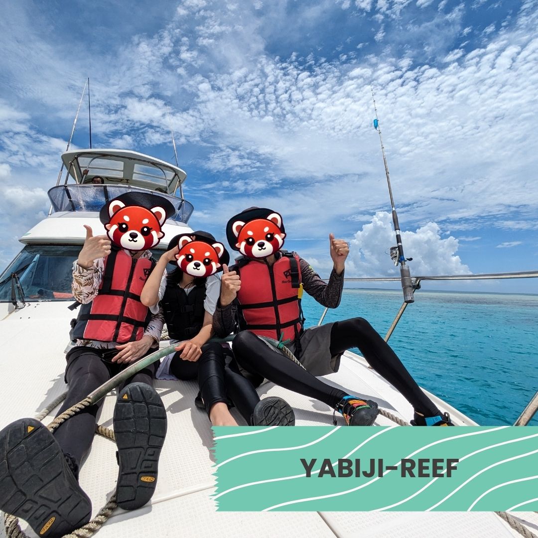 Family posing on a boat during a tour to Yabiji Reef in clear blue ocean.
