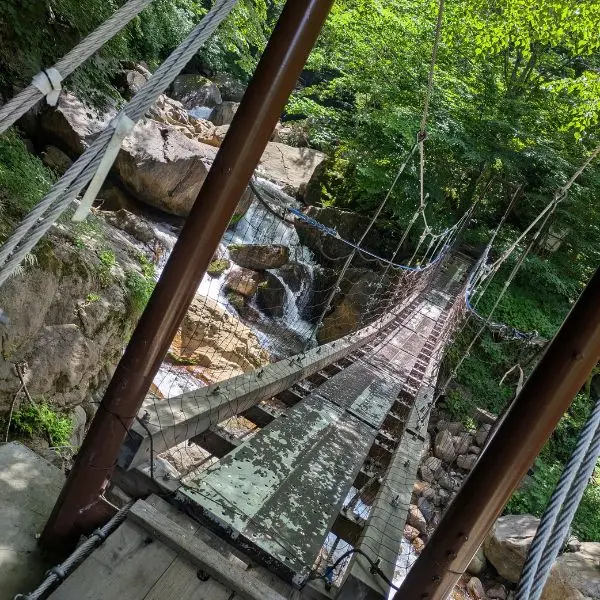 Suspension bridge and clear stream along the Nagano waterfall hike to Yonako Falls
