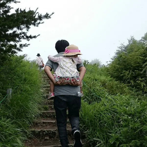 Parent carrying child up the mountain trail – perfect example of family-friendly Japan travel.