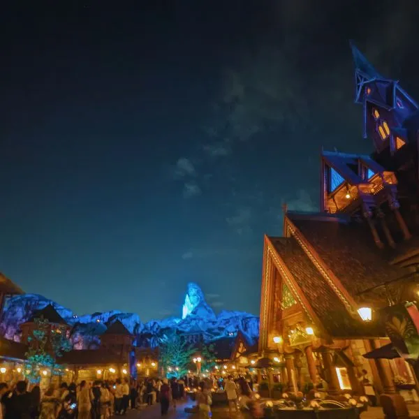Night view of Fantasy Springs Frozen area at Tokyo DisneySea, glowing with colorful lights and castle reflections.
