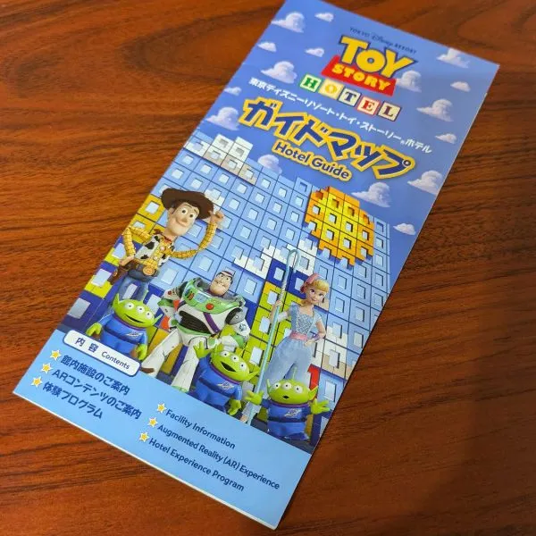 Toy Story Hotel guide leaflet near front desk with Woody, Buzz, and Little Green Men illustrations.