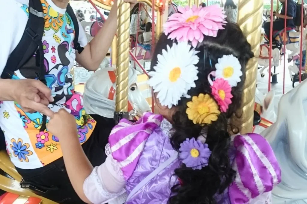 Little girl in a princess dress riding a carousel with her parent in Japan, capturing the magic of a Japan family travel guide 2025 experience.
